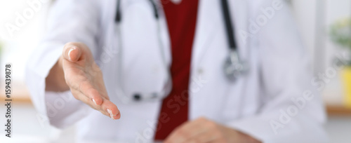 Female medicine doctor offering helping hand in office closeup. Physician ready to examine and save patient. Friendly and cheerful gesture © rogerphoto