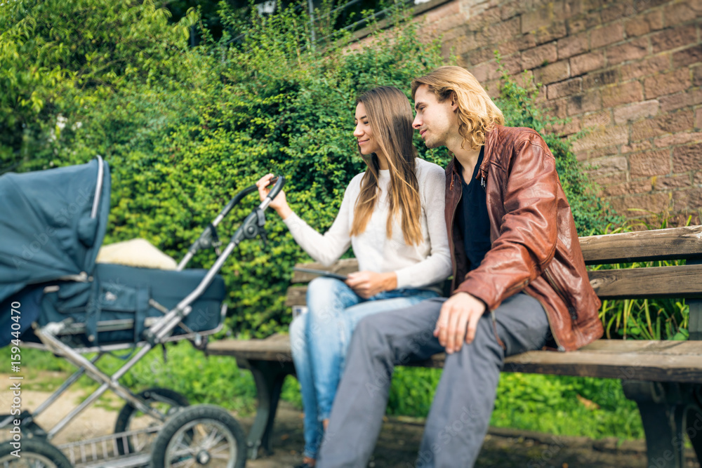 Fototapeta premium Young Parents With Baby Stroller In The Park