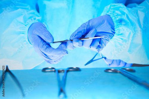 Close-up of of surgeons hands at work in operating theater toned in blue