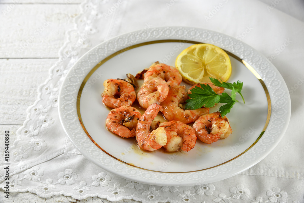 fried tiger prawns, marinated with garlic, spices, herbs and lemon on a fine white plate, italian parsley garnish, copy space on the bright background fried tiger prawns, marinated with garlic, spices, herbs and lemon on a fine white plate, italian parsley garnish, copy space on the bright background