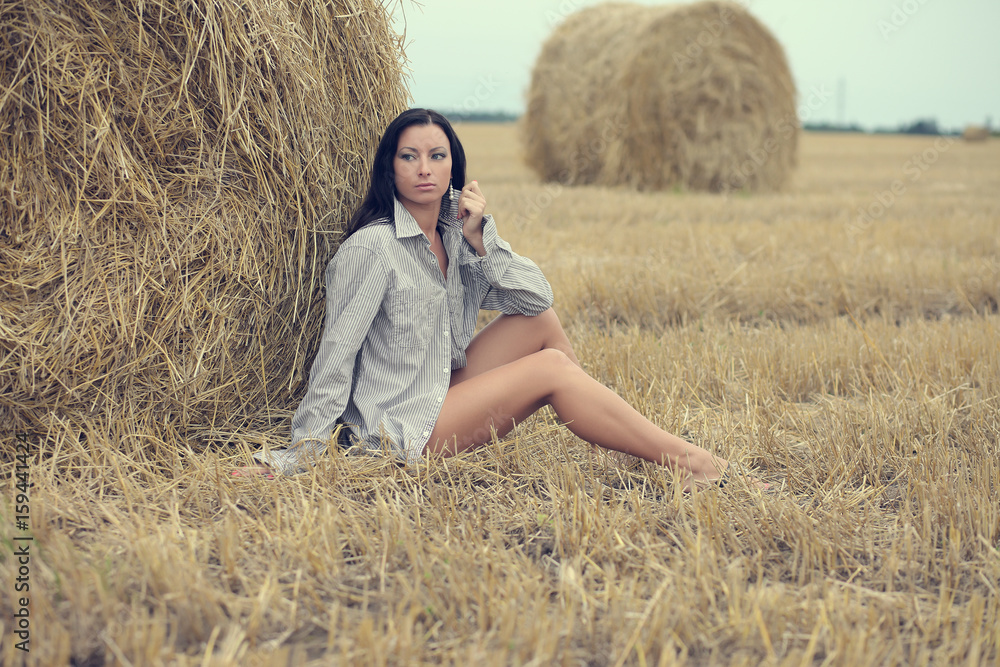 woman sitting in field with haystacks woman sitting in field with haystacks