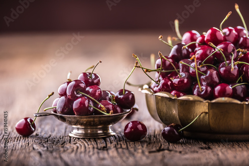 Cherries. Fresh sweet cherries. Delicious cherries with water drops in retro bowl on old oak table.
