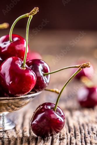 Cherries. Fresh sweet cherries. Delicious cherries with water drops in retro bowl on old oak table.