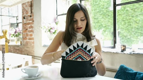 Elegant woman taking blush from her bag and applying on cheeks, steadycam shot
