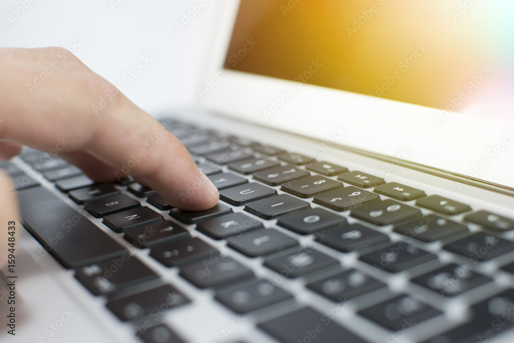 Closeup of a man's hand using a laptop. Silver aluminum body. A beautiful modern laptop. A keyboard of a laptop isolated on a white background. Lens flare in the background.