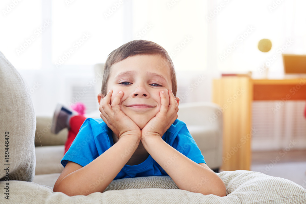 Young smiling boy lying on sofa and leaning on his hands Young smiling boy lying on sofa and leaning on his hands