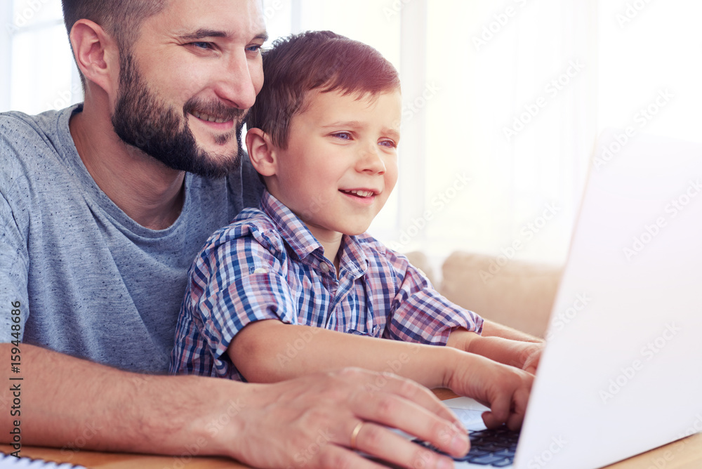 Happy father with son playing computer games on laptop