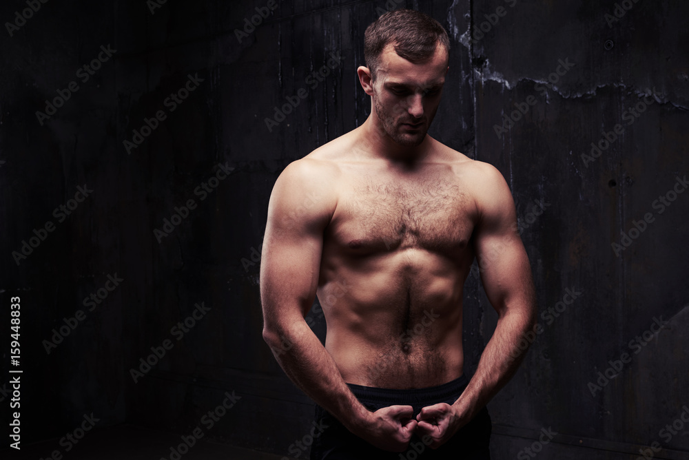 Shirtless man looking at his pumped biceps