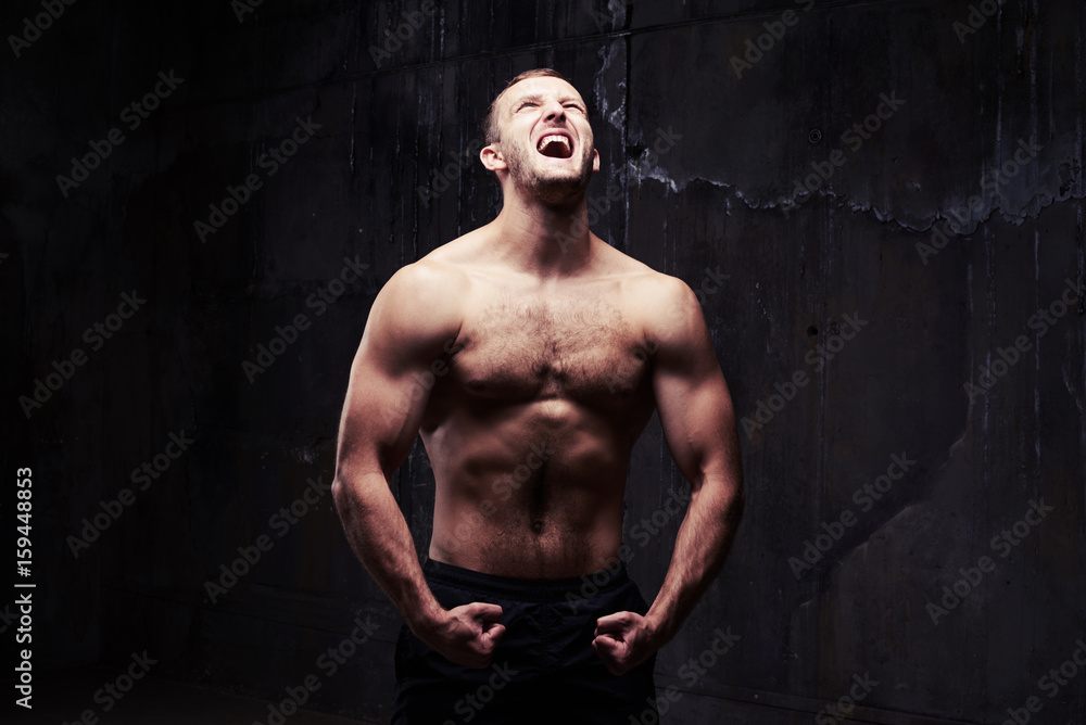 Man screaming while holding wrists together showing his pumped muscles
