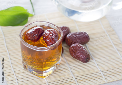 A glass cup of Chinese red date tea on the table. Chinese red dates are believed to be a nutritional supplement that helps promote production of red blood cells. photo