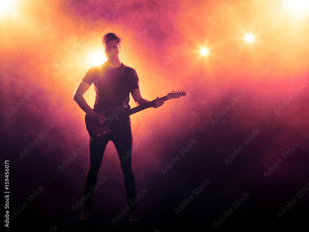 Silhouette of a guitar player with guitar on orange smoke background, backlit