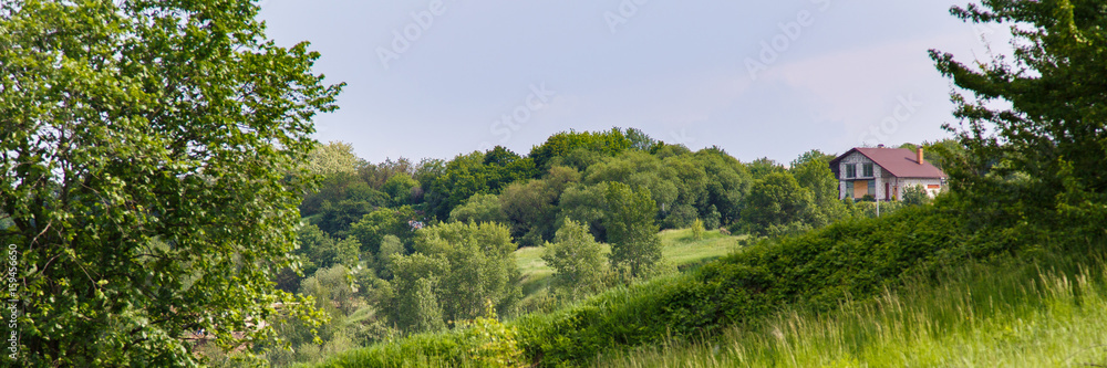 House on a hill. Landscape of green hills with a village on them