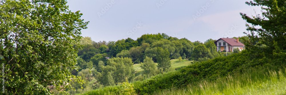 House on a hill. Landscape of green hills with a village on them House on a hill. Landscape of green hills with a village on them