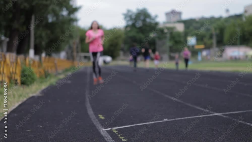 A young girl is running at the stadium. Playing sports. Girl running sport.