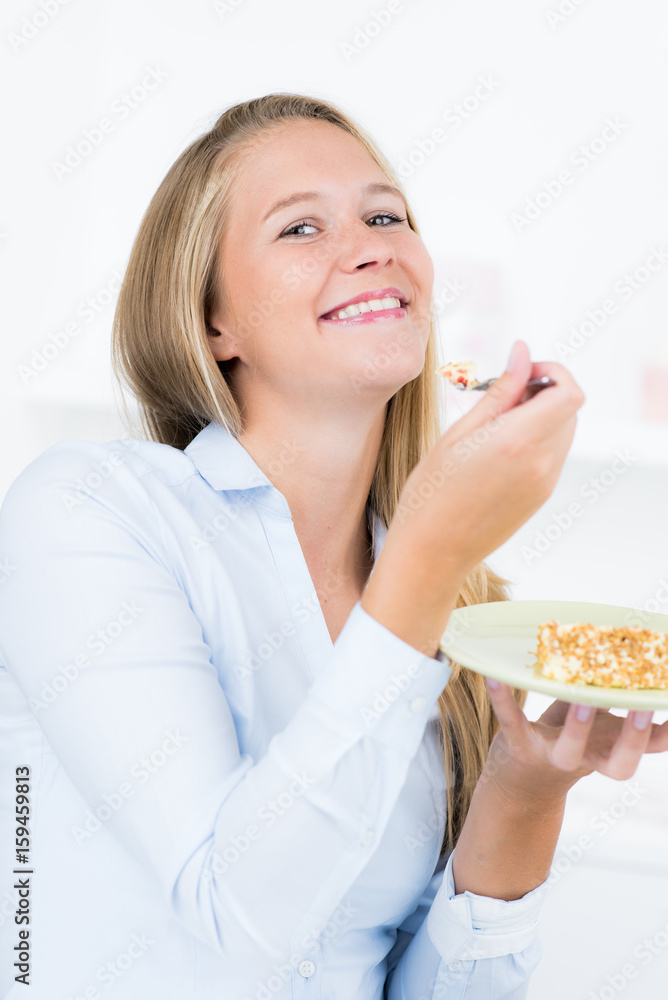 Blonde junge Frau isst ein Stück Kuchen