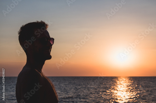 Silhouette of a young man enjoying sunset by the sea