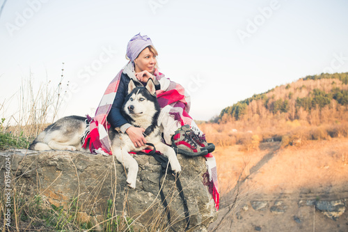 A young girl sits with her friend the husky dog on the edge of the gorge at sunset © yanik88