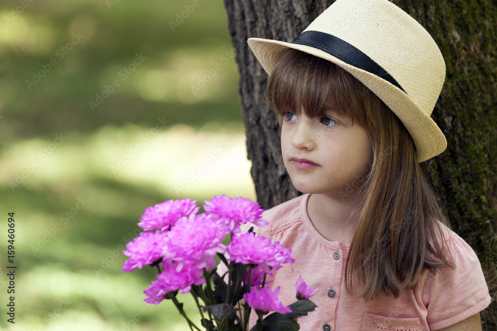 Little cute girl standing in a park and holding a bouquet and waiting for her mother
