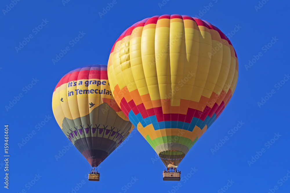 Fototapeta premium Balloons fly over California grape vineyard and winery during Hot Air Balloon Festival