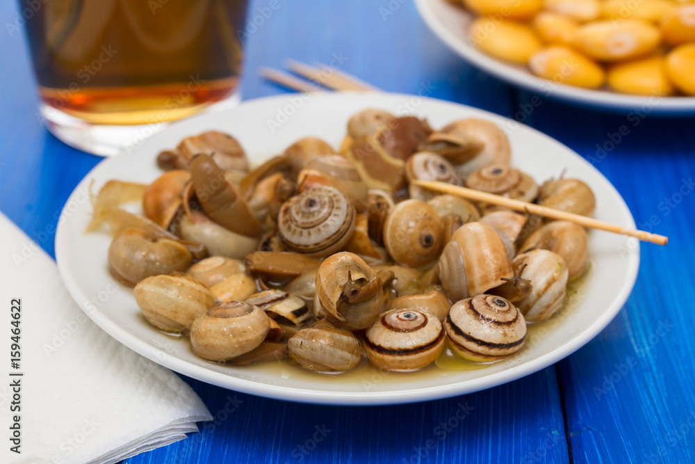 salted lupins on white plate and snails with glass of beer