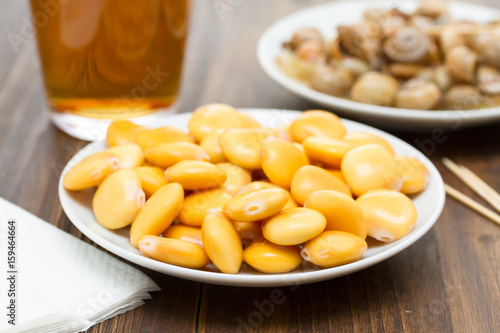 salted lupins on white plate and snails with glass of beer