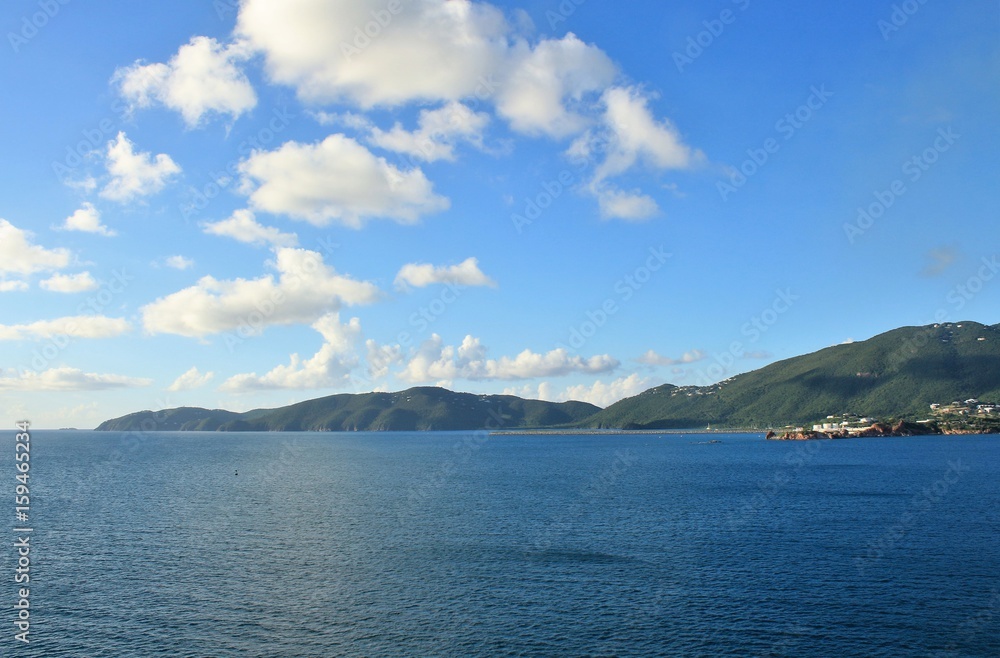 Ocean and mountain landscape with blue sky and white clouds