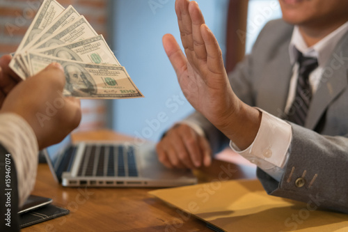 Businessman rejecting money cash banknote from a man.  honest business people in suit refuse to take the bribe - anti bribery, corruption, venality concept. photo