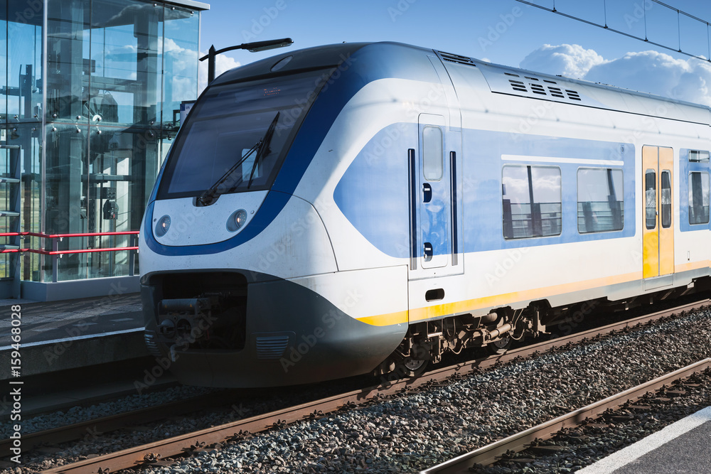 Naklejka premium Pociąg elektryczny jedzie w pobliżu peronu kolejowego