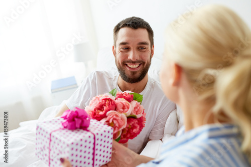 happy couple with gift box in bed at home