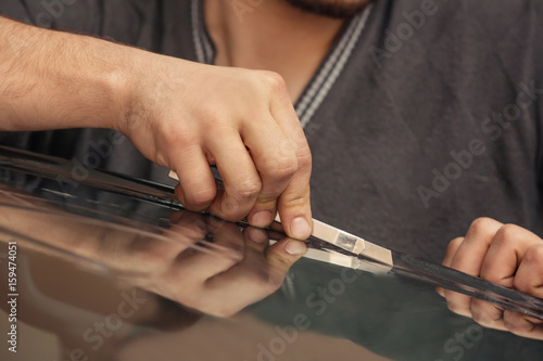 Worker applying tinting foil onto car window