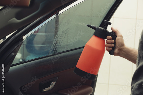 Worker spraying water onto car window
