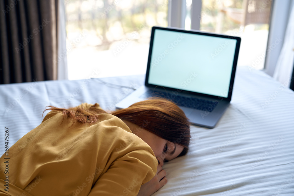 Fototapeta premium Woman is tired, woman is lying in bed with laptop