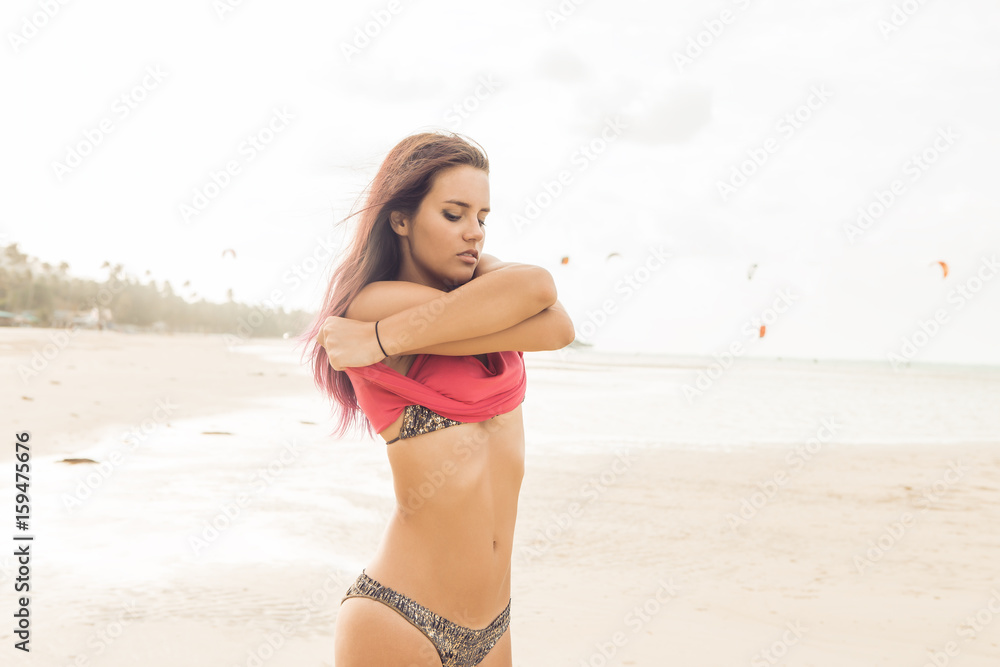 Sexy slim woman in sensual bikini on a tropical beach undress pink t-shirt  and erotic