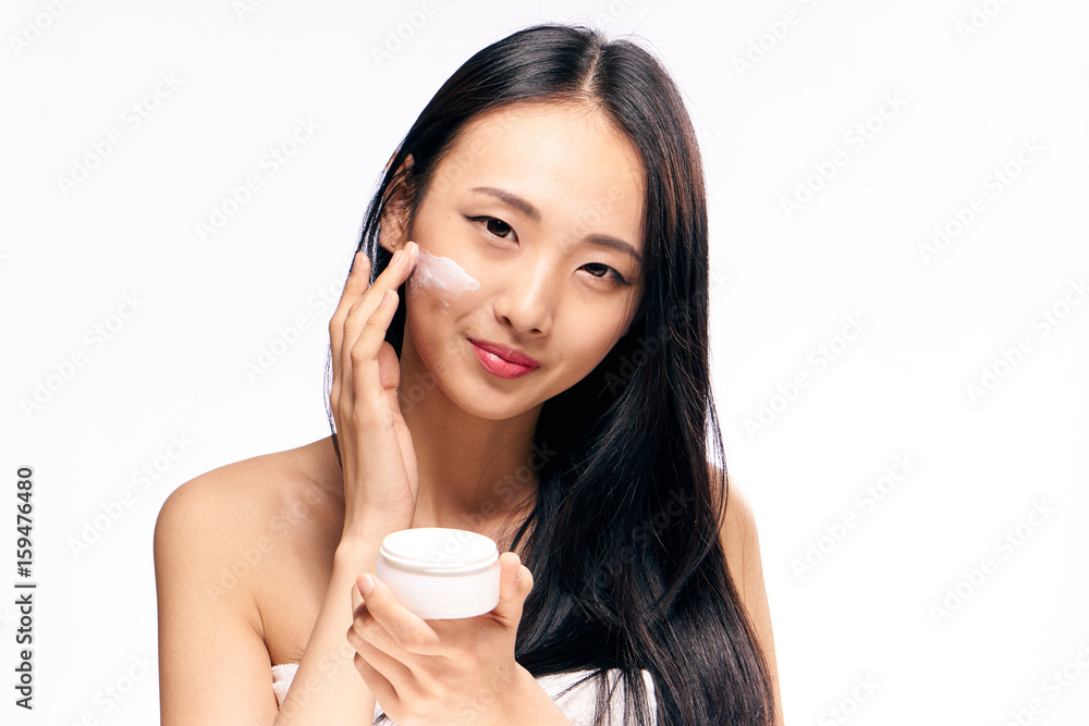 Woman puts cream on face on isolated background Woman puts cream on face on isolated background