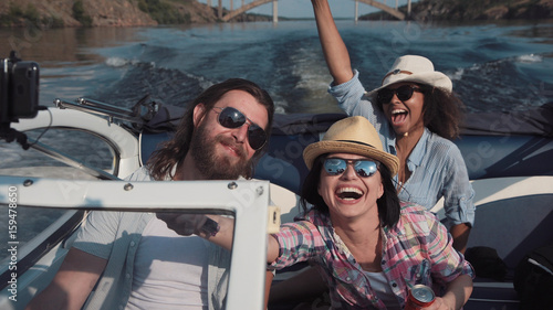 Картината върху платно Laughing family or three friends wearing sunglasses riding in a speedboat on a l
