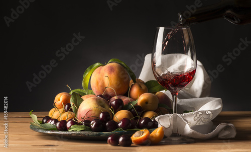 glass with red wine and tray with fruits