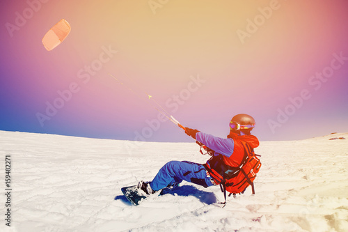 Snowboarder with a kite on fresh snow in the winter in the tundra of Russia against a clear blue sky. Teriberka, Kola Peninsula, Russia. Concept of winter sports snowkite.