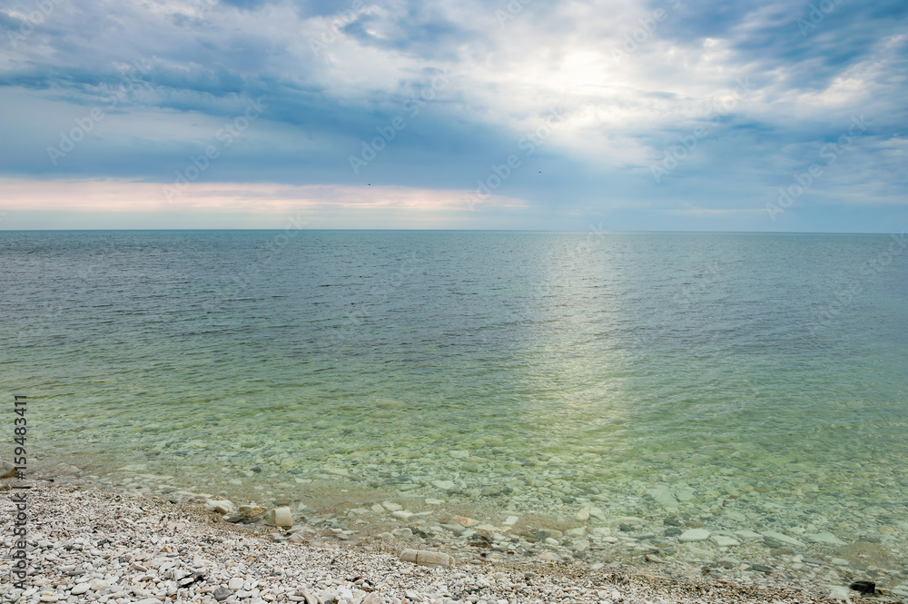 Calm sea with transparent green water under clouds Calm sea with transparent green water under clouds