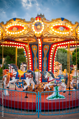 Carousel with lights in evening under stormy clouds