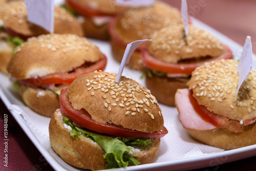 Small burgers served on a plate with flags pinned