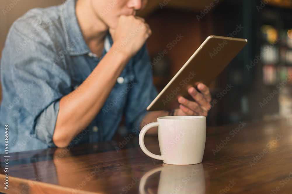 Young man drinking coffee in cafe and using tablet computer Young man drinking coffee in cafe and using tablet computer