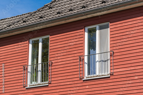 Fenster in einer roten Fassade aus Holz