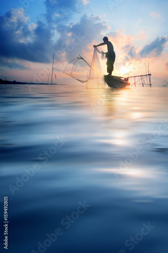 Fishermen on boat fishing with a fishnet,the old traditional equipment of Thai fishery.Silhouette scene in Pak Pra Village, Pattalung province, Thailand.