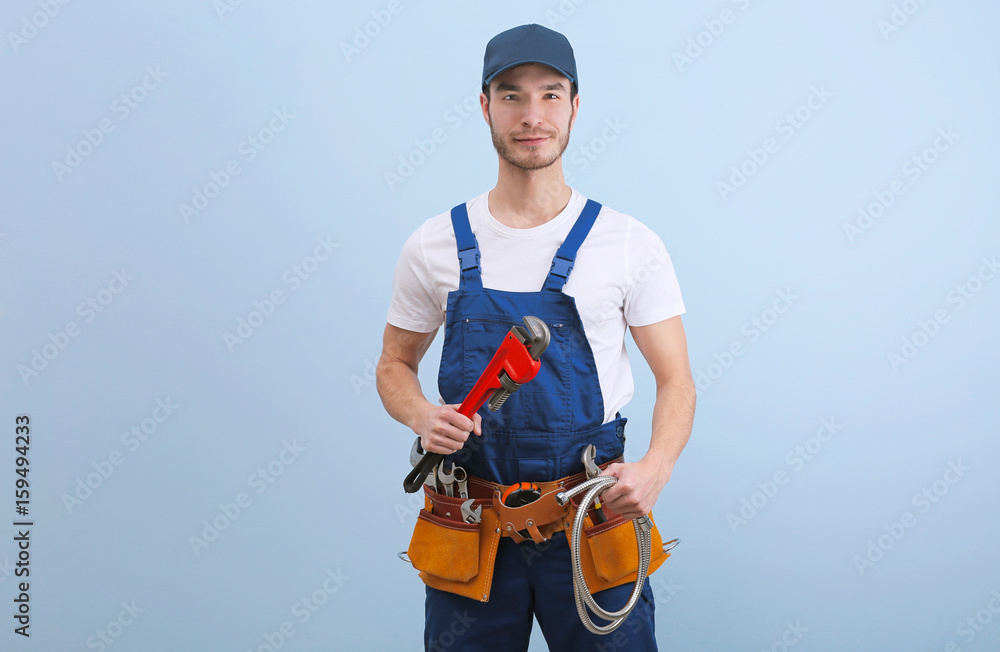 Naklejka premium Handsome young plumber in uniform on color background
