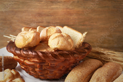 Baked basket with fresh bread on wooden background