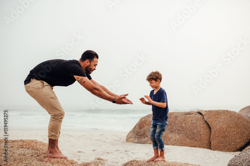 Father and son playing on the rocky beach photo