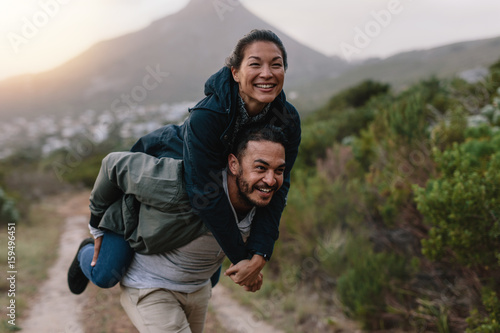 Fototapeta Couple enjoying piggyback ride in countryside