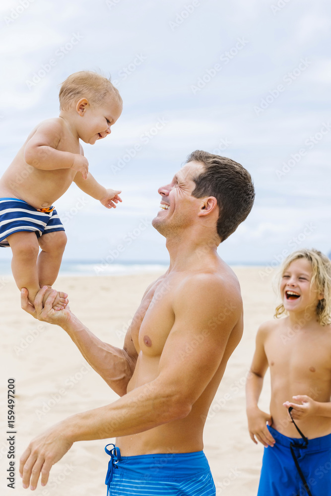 Father playing with sons (12-17 months, 8-9) on beach Father playing with sons (12-17 months, 8-9) on beach