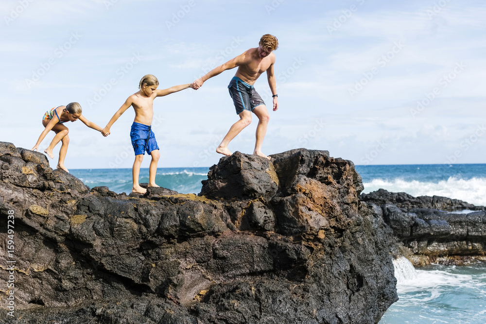 Man and children walking on rock by sea Stock Photo | Adobe Stock