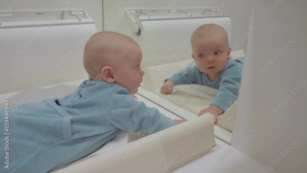 Beautiful baby playing with mirror and kisses his reflection. 6 month old baby. Beautiful baby playing with mirror and kisses his reflection. 6 month old baby.